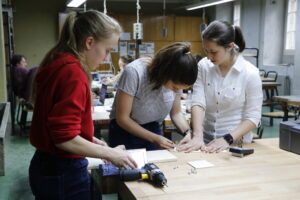 Drei Mädchen arbeiten an einer Werkbank, ein Akku-Schrauber liegt auf dem Tisch.