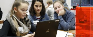 Drei Mädchen sitzen konzentriert vor einem Laptop.