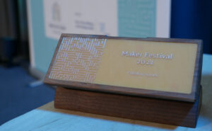 Der Award ist aus Holz. Vorne darauf befindet sich ein Platinenmuster in die Aufschrift: Maker Festival 2021 - Publikumspreis