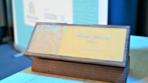 Der Make-Your-School-Award 2021 ist aus Holz und einem Platinenmuster gefertigt. Auf der Vorderseite seht Maker Festival 2021, Publikumspreis