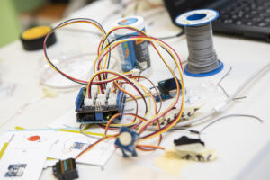 An einem Mikrocontroller sind mit vielen bunten Kabeln Sensoren und ein kleiner Motor angeschlossen.