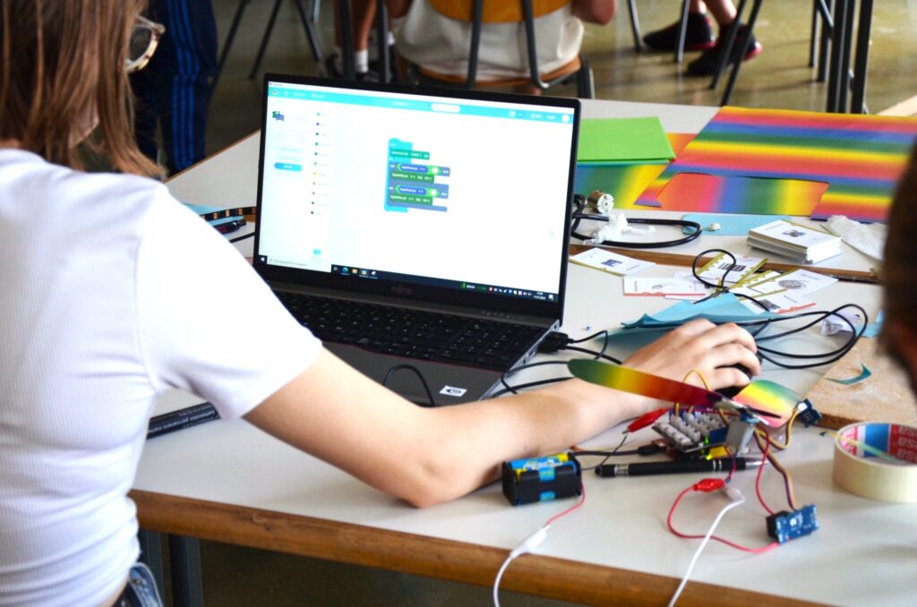 Eine junge Person sitzt vor einem Laptop und programmiert mit einer blockbasierten Sprache.